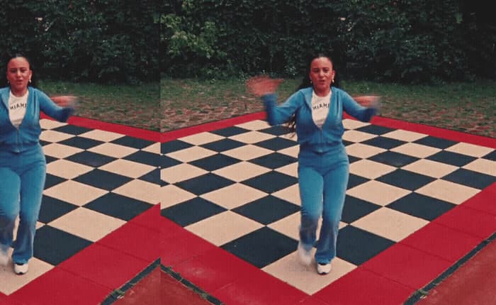 a woman in a blue suit is dancing on a checkered floor