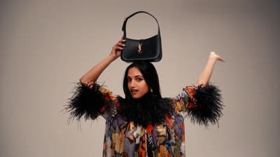 a woman holding a black purse over her head