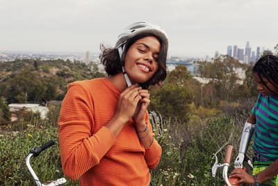 a woman standing next to another woman on a bike