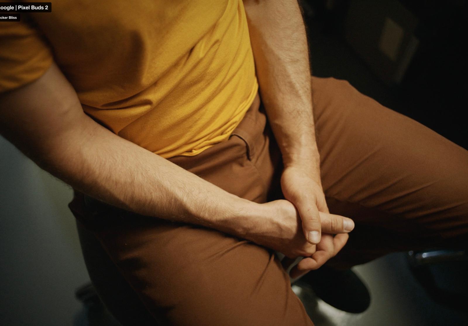a man sitting on a toilet with his hands on his knees