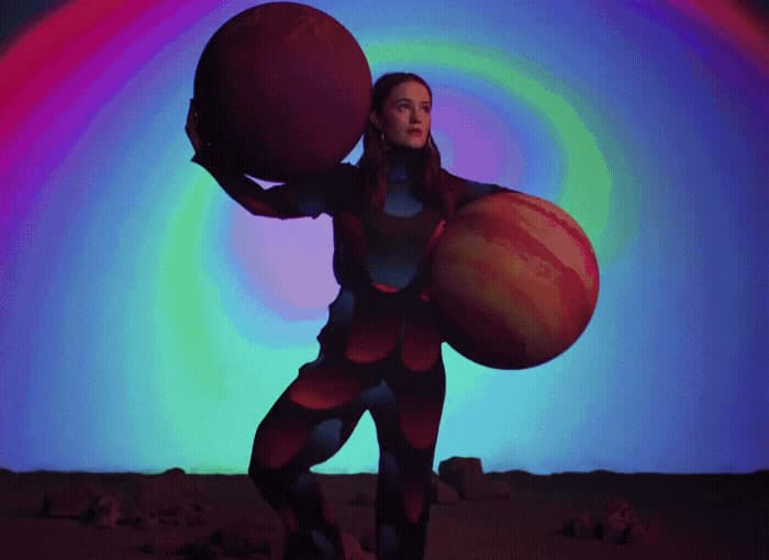 a woman holding a large ball in front of a colorful background