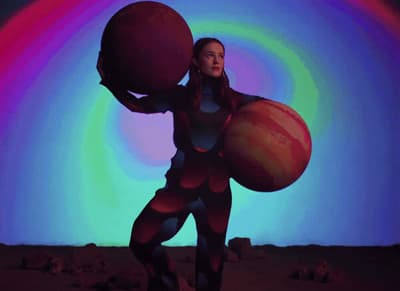 a woman holding a large ball in front of a colorful background