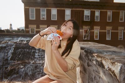 a woman sitting on a ledge eating a donut