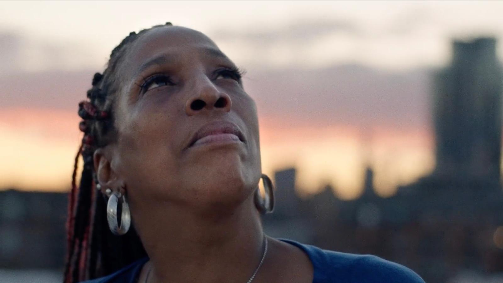 a woman looking up at the sky with a city in the background