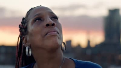 a woman looking up at the sky with a city in the background