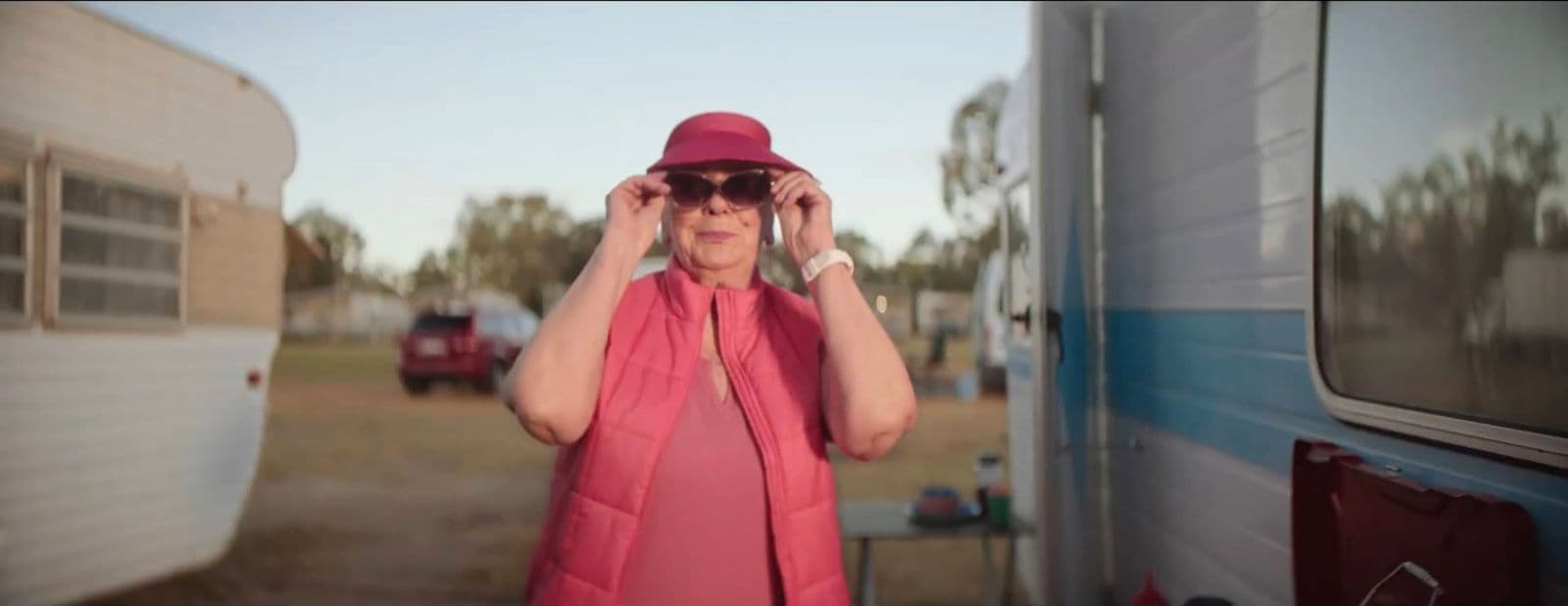 a woman in a red hat and sunglasses standing in front of a trailer