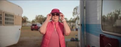 a woman in a red hat and sunglasses standing in front of a trailer