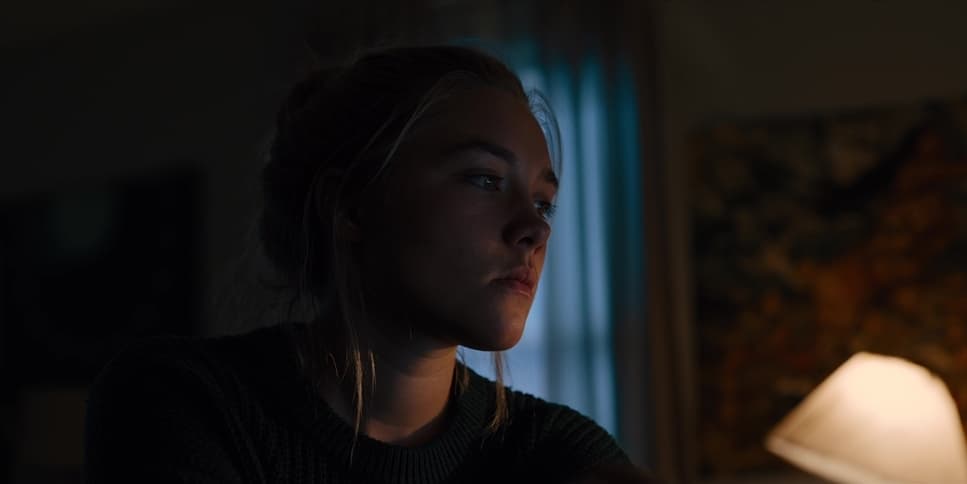 a woman sitting in front of a lamp in a dark room