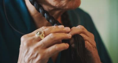 a woman is braiding her hair with a ring