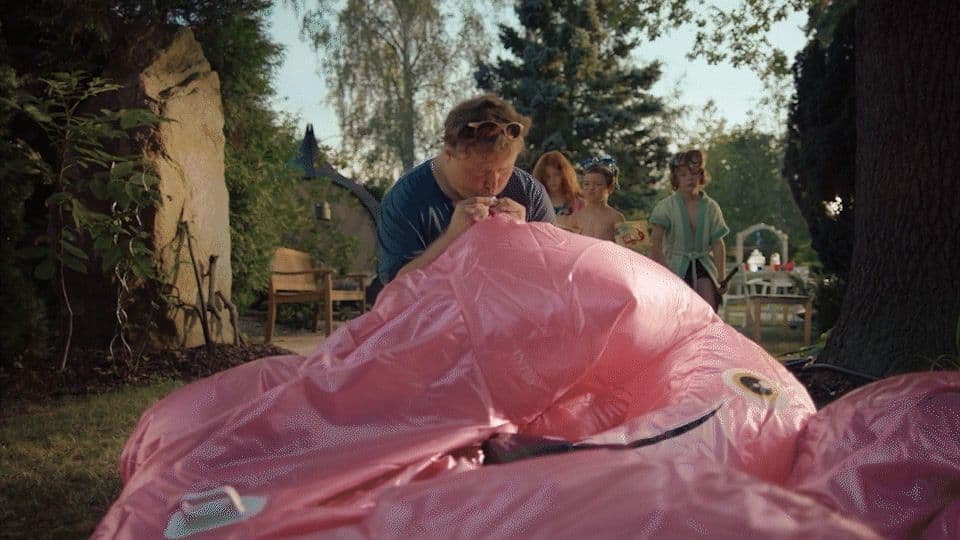 a group of people standing around a large pink object