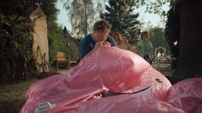 a group of people standing around a large pink object