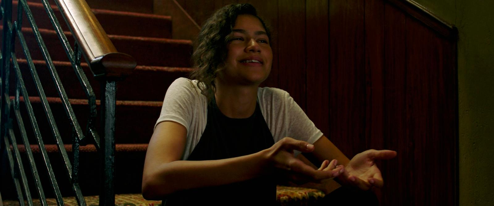 a woman sitting on the ground in front of a stair case