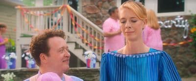 a woman standing next to a man in a blue dress