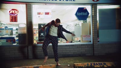 a woman is jumping in the air in front of a store