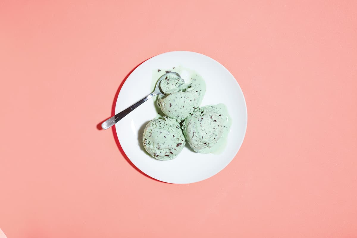 a white plate topped with green cookies on top of a pink table