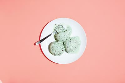 a white plate topped with green cookies on top of a pink table