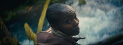a young boy standing in front of a waterfall