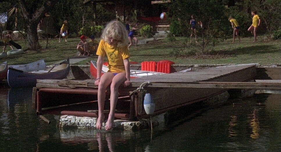 a woman sitting on a dock next to a body of water