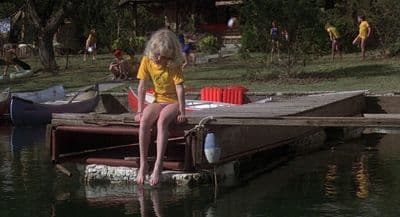 a woman sitting on a dock next to a body of water