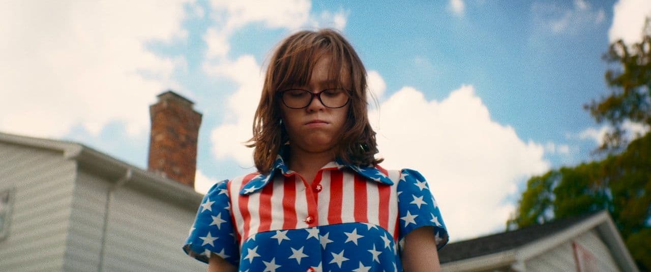 a young girl wearing glasses and an american flag shirt