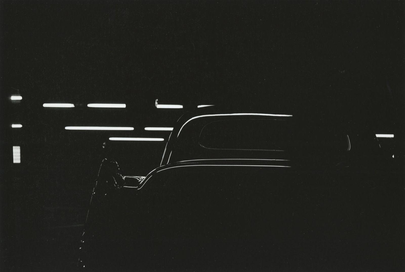 a black and white photo of a car in the dark