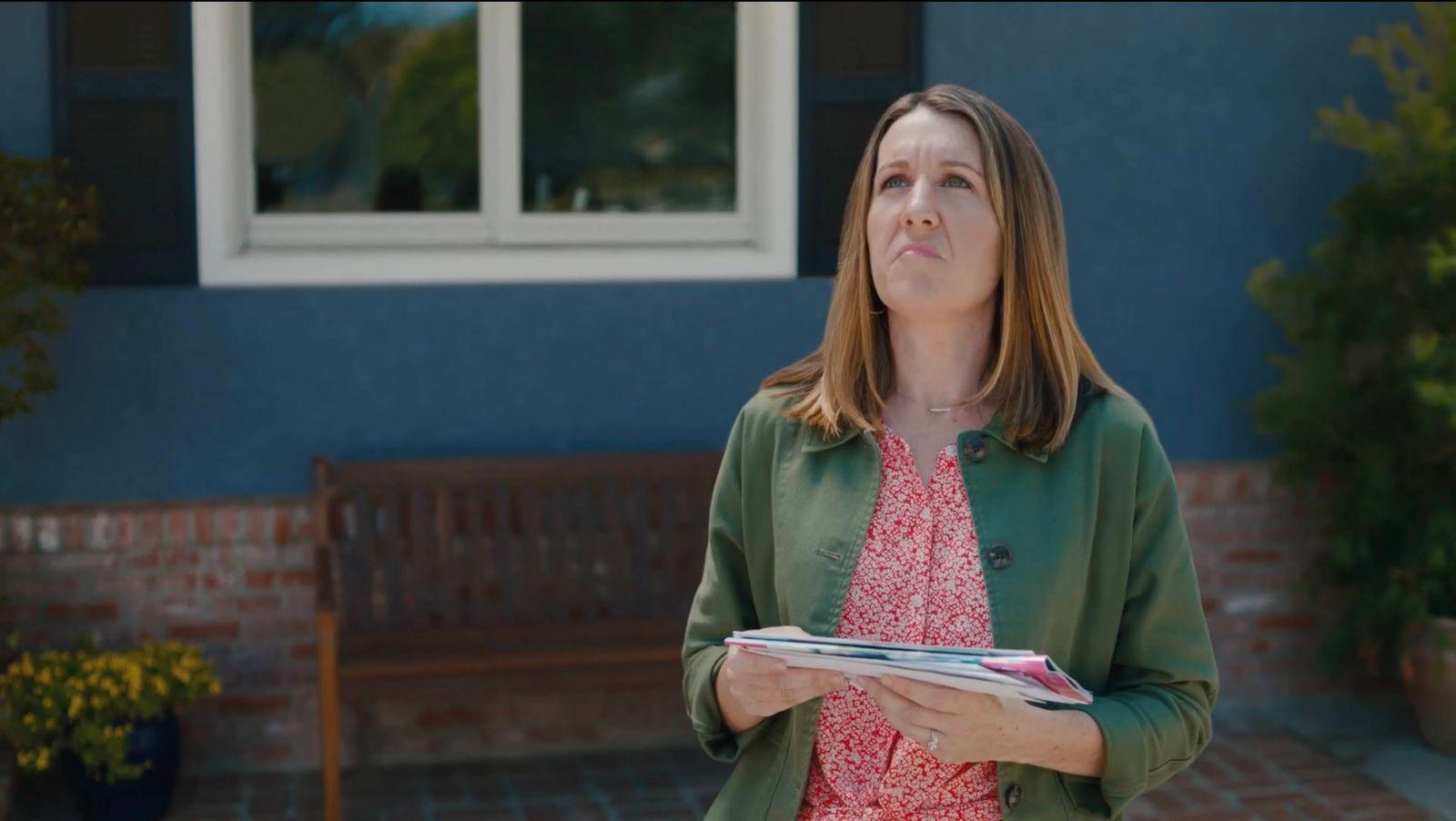 a woman holding a binder in front of a house