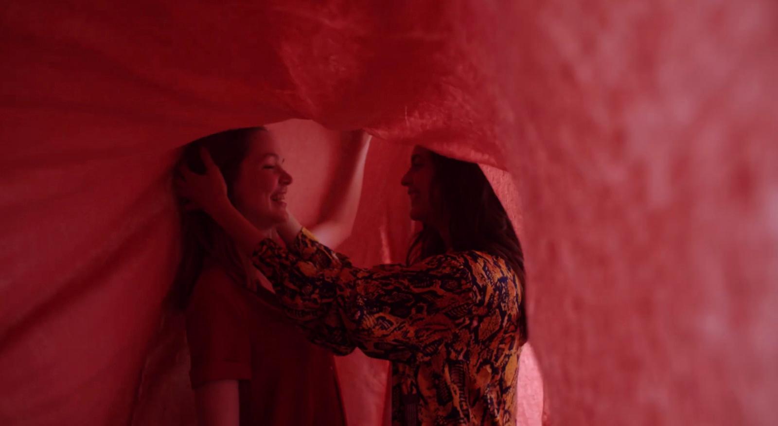 two women are standing in a red room