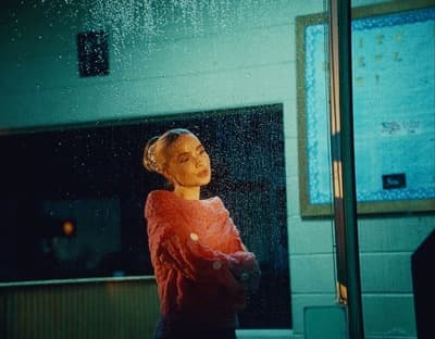 a woman standing in front of a window in the rain