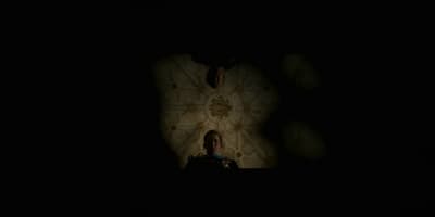 a person in a dark room with a clock on the wall