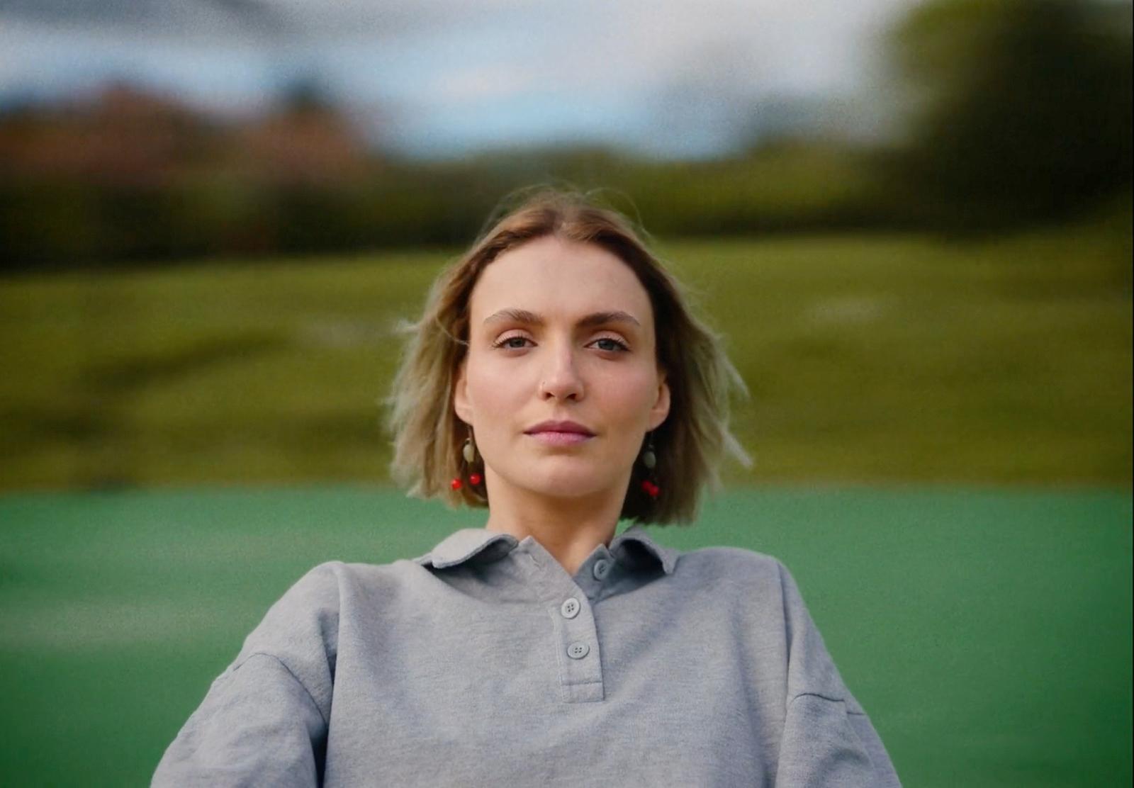 a woman in a gray shirt holding a tennis racquet