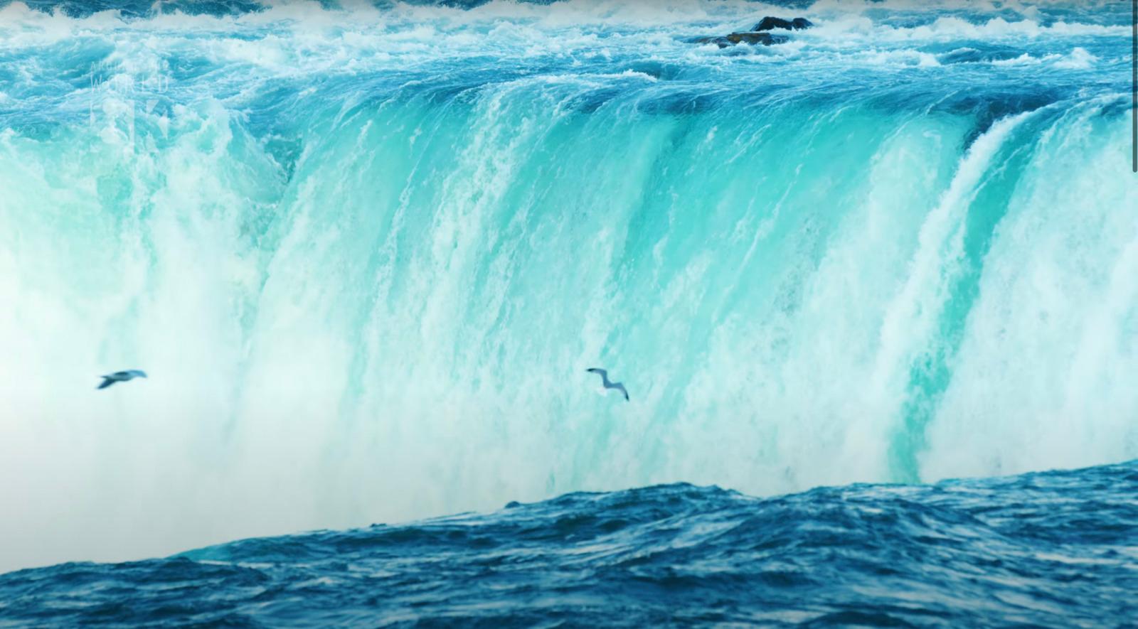 two birds flying over a large waterfall in the ocean