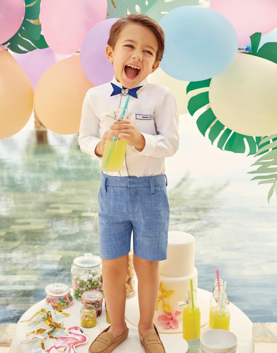 a young boy standing in front of a cake