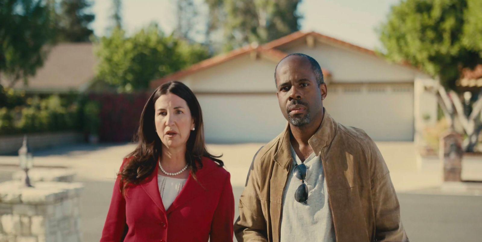 a man and a woman standing in front of a house
