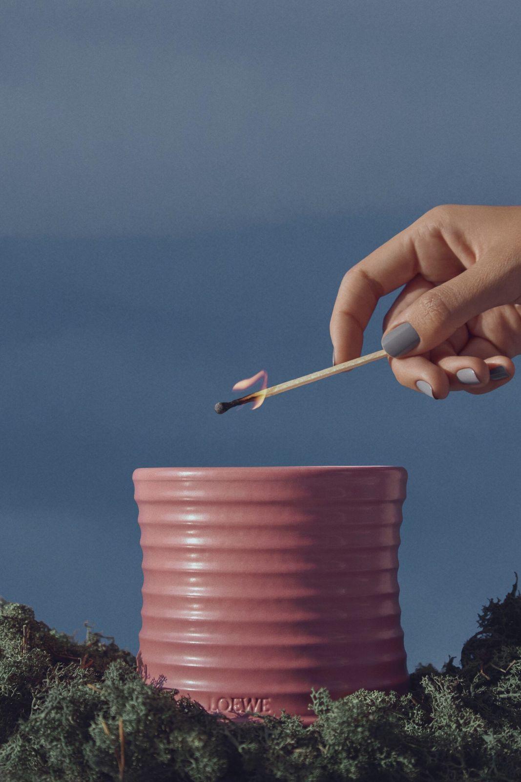 a hand holding a toothpick over a pink cup