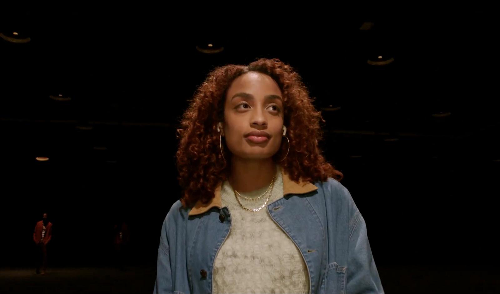 a woman with curly hair standing in the dark