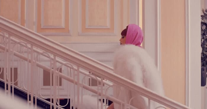 a woman with a pink head scarf walking down a set of stairs