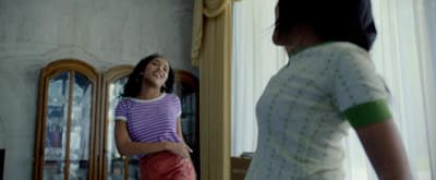 a young girl standing in front of a mirror
