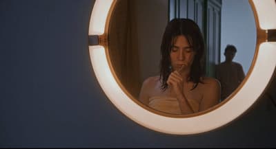 a woman standing in front of a mirror brushing her teeth