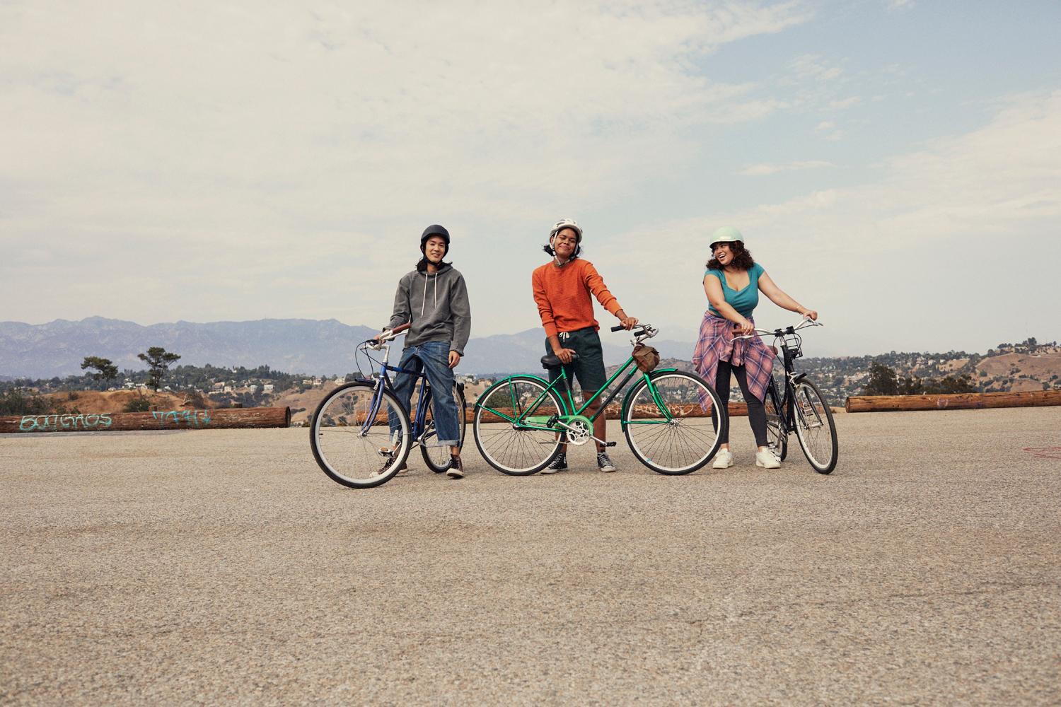a group of three people standing next to each other on bikes