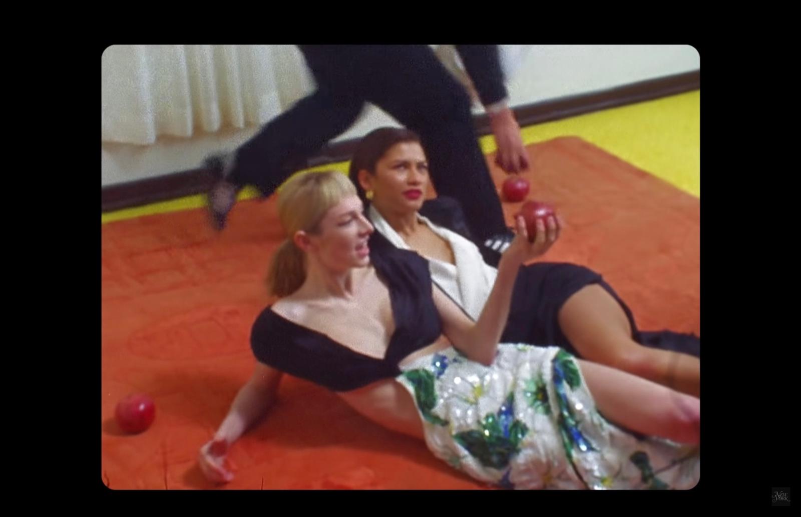 two women are sitting on the floor and one is holding an apple