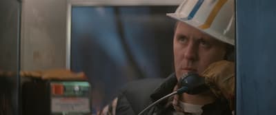 a man with a hat on talking into a microphone