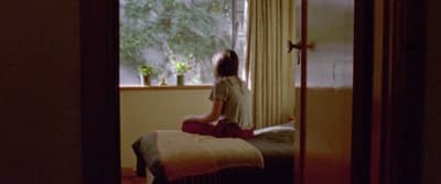a woman sitting on a bed looking out a window