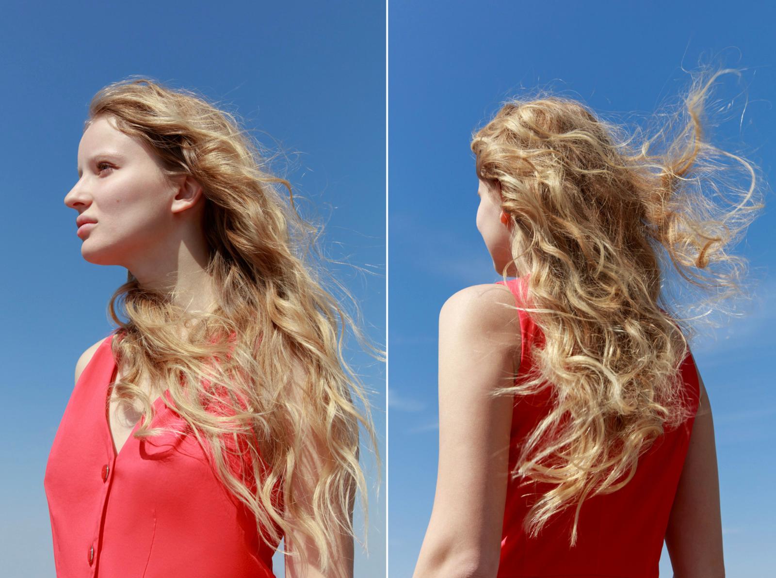 a woman with long blonde hair standing in front of a blue sky