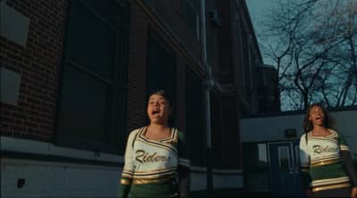 two women in cheerleader outfits standing in front of a building