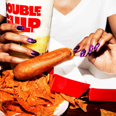 a woman holding a hot dog and a cup of coffee