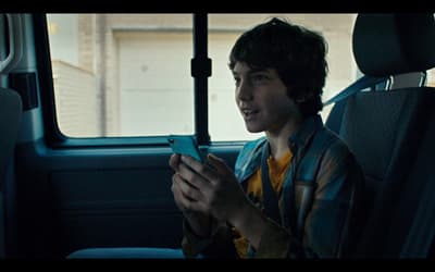 a young boy sitting in the back seat of a car looking at a cell phone