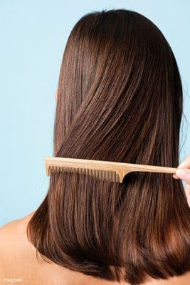 a woman brushing her hair with a wooden comb