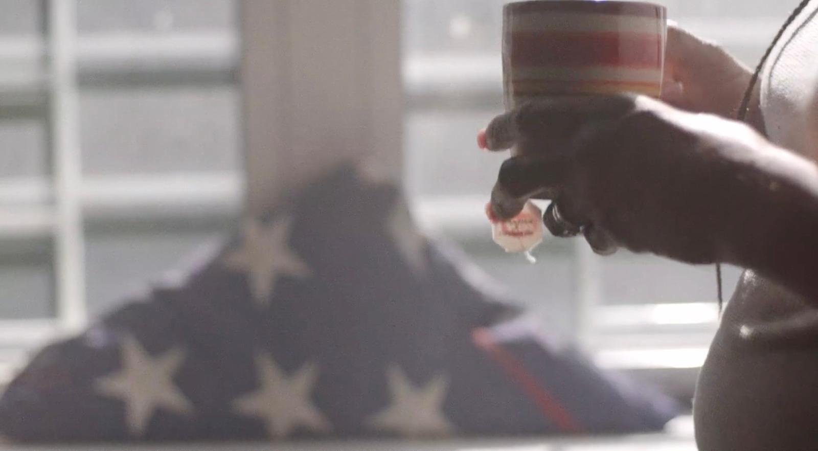 a person holding a cup of coffee in front of an american flag