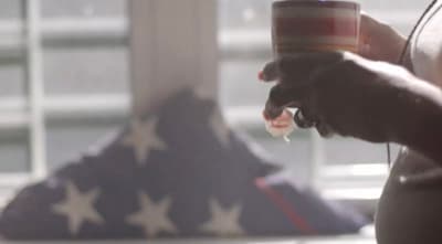 a person holding a cup of coffee in front of an american flag