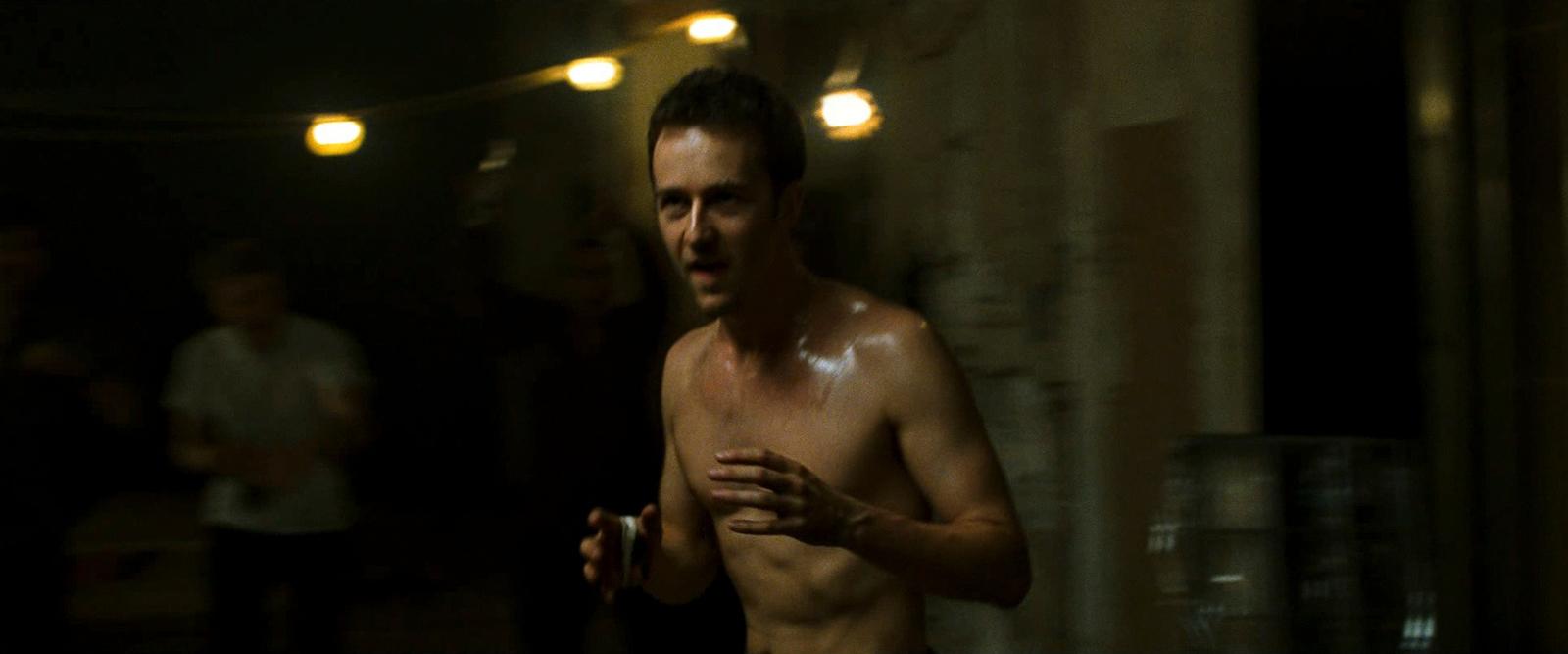 a man without a shirt is standing in the dark